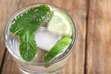 Fresh cocktail with mint, ice and lime on wooden table background