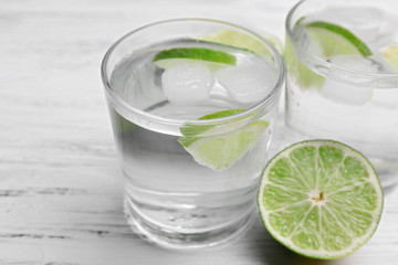 Fresh cocktails with ice and lime on white wooden table background