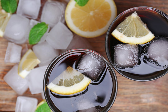 Two glasses of cola with cubes of ice and lemon, closeup