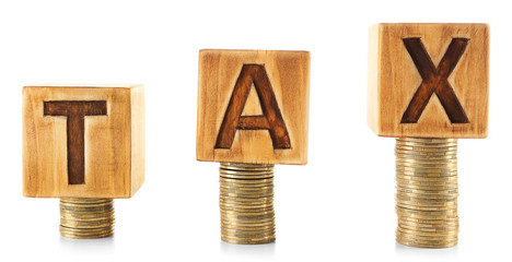Word TAX written on wooden cubes on stacked coins isolated on white