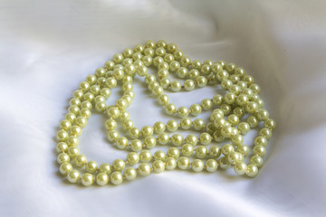 Pearl necklace on white silk fabric soft