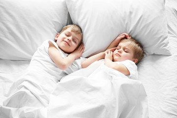 Cute boys sleeping in bed under blanket, closeup
