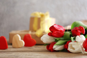 Bouquet of red and white tulips in a paper bag on a wooden table, close up