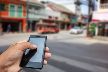 Hand hold and touch screen smart phone, tablet,cellphone in city blur.