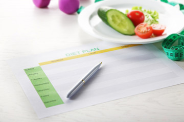 Plate of vegetables and diet plan on a table
