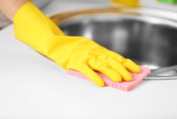 Female hand with sponge cleaning a sink in the kitchen