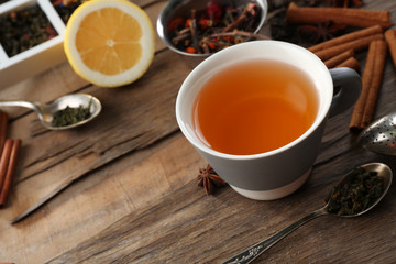 Cup of brewed tea with spices and lemon on wooden table