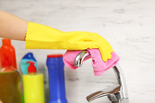 Female hand with rag cleaning a tap in the kitchen