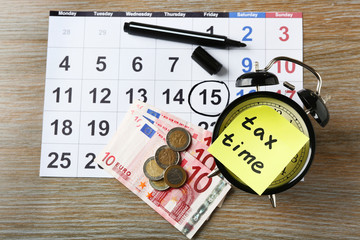 Tax time on alarm clock with euro, marker and calendar