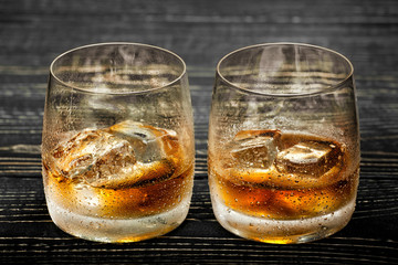 whiskey with ice on a black wooden background