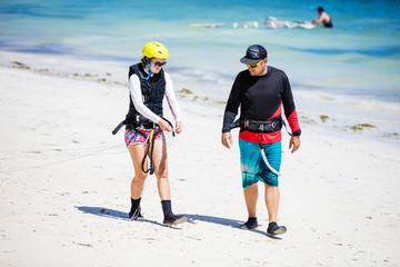 Kitesurfing instructor and female student preparing lines on beach