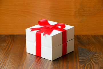Gift box with red bow on wooden background.