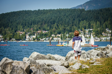 Little boy watching the boats from the shore