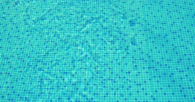 View the the clear rippling water in blue tiled swimming pool on sunny summer day. Vacation and recreation