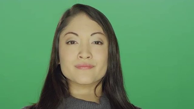 Beautiful young Asian woman looking proud, on a green screen studio background