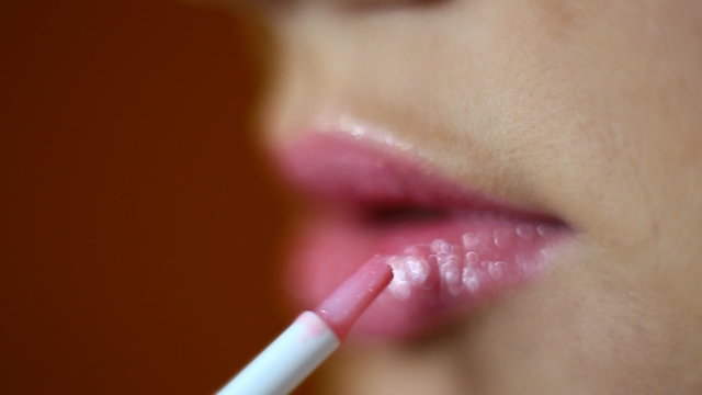 girl paints her lips close-up