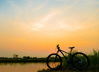 silhouette MTB, bicycle in grass at sunset