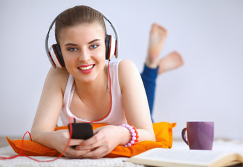 Naklejka premium Young woman lying on floor and listen to music