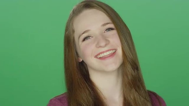 Cute redhead smiling, on a green screen studio background