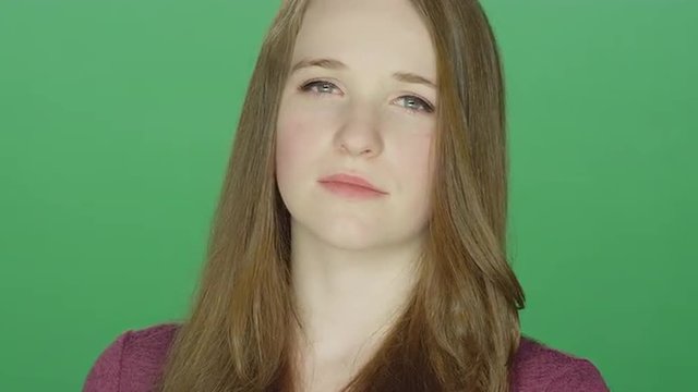 Cute redhead staring with an attitude, on a green screen studio background