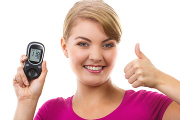 Woman holding glucometer and showing thumbs up, checking and measuring sugar level, concept of...