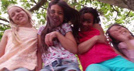 Little girls sitting on fence under a treehouse in summer - Powered by Adobe