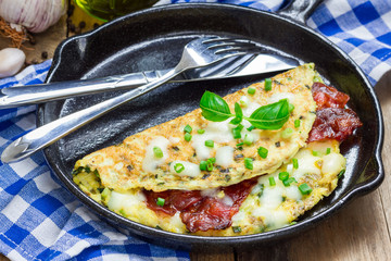 Bacon stuffed omelette with backed beans on a iron cast pan - obrazy, fototapety, plakaty