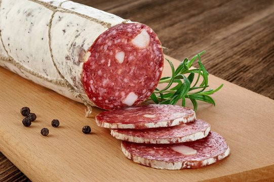 Dried salami with white mold on a wooden background.