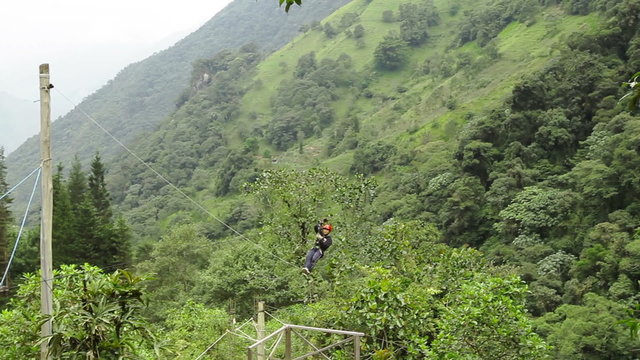 tourist sliding on zip-line at high velocity is stopped down by emergency braking system tracking shot run sport zipline canopi tourist water flow vegetation nature canopy outdoor adventure river ecu