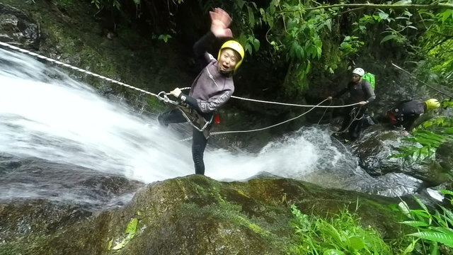 Watch an adventurous Asiatic girl rappelling down a stunning waterfall in the lush Ecuadorian rainforest in slow motion,captured by a static camera.