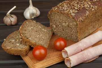 Freshly baked whole wheat bread. Preparing homemade breakfast. Various ingredients for the meal. Sliced bread on cutting board. Advertising on the bakery.
