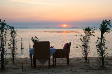Romantic little table on the seashore, with candles, at sunset