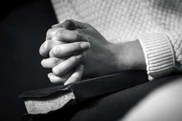 Woman prays with folded hands on the bible