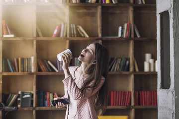 Smart beautiful young woman in headphones with a glass of coffee
