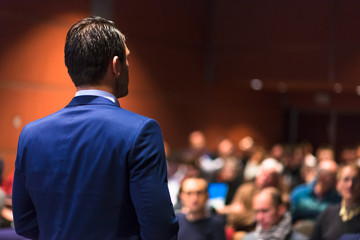 Speaker giving a talk on corporate Business Conference. Audience at the conference hall. Business...