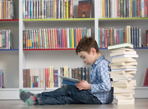 Cute boy reading book in library
