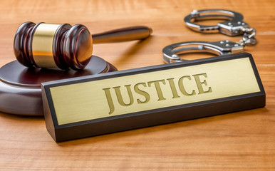 A gavel and a name plate with the engraving Justice