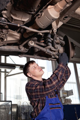 Fototapeta na wymiar Car mechanic inspecting car wheel and suspension detail of lifte