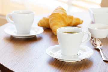 Two cups of coffee with croissants.