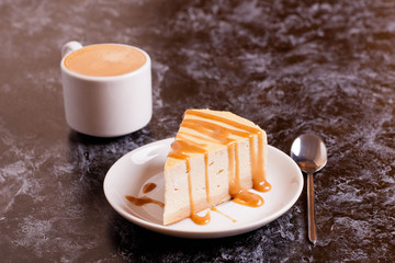 Slice of cheesecake with caramel sauce, cup of coffee