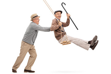 Two senior gentlemen swinging on a swing