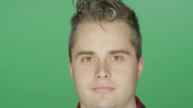 Young man staring ahead, on a green screen studio background