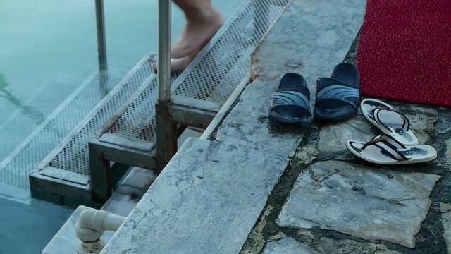 Man Takes Off His Sandals and Walks Down in Pool. 4k