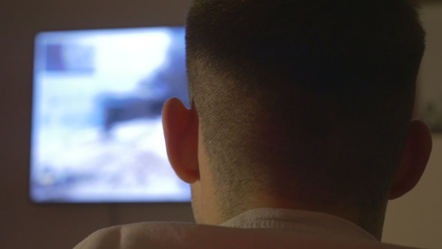 Rear view of a young man playing on a console