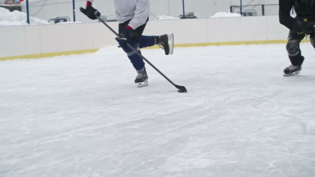Hockey defenseman falling down on ice while knocking the puck off the stick of a puck carrier during a practice at outdoor rink 