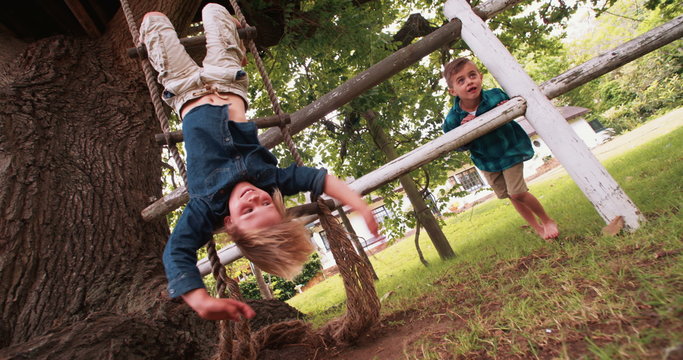 Little boy hanging from a rope ladder smiling at camera