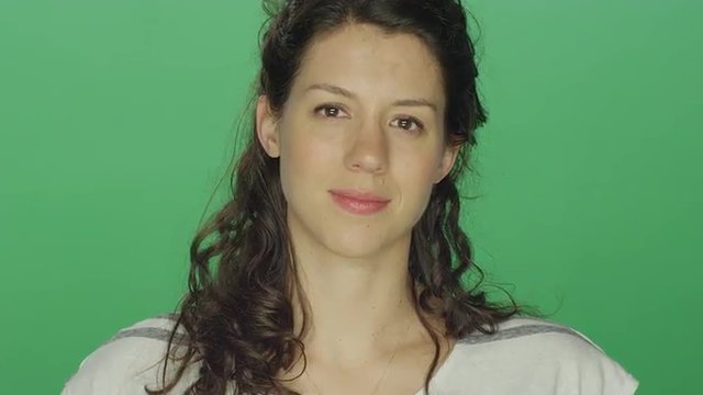 Young woman looking forward pleasantly, on a green screen studio background