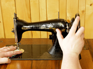 hands working with vintage mechanical sewing machine