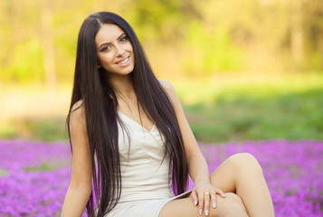 Fototapeta premium Portrait of a sensual young brunette female on field in sexy dress 