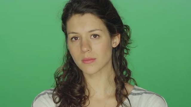 Young woman looking sad, on a green screen studio background